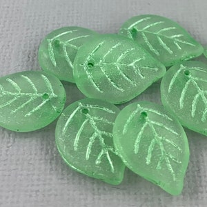 May include: A group of ten light green glass leaf beads with a frosted finish. Each bead has a small hole for stringing.