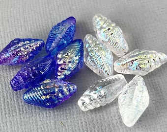 May include: A collection of iridescent glass beads shaped like seashells. Half of the beads are clear and half are blue.
