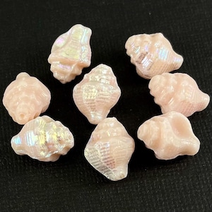 May include: Eight iridescent pink seashells with a pearlescent finish. The shells are approximately 1 inch in size and have a smooth, polished surface.
