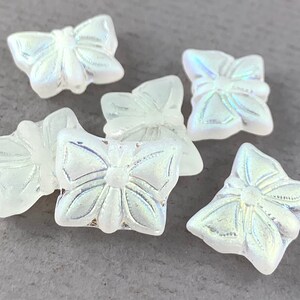 以下が含まれることがあります： 虹色の白いガラス製の蝶のビーズが6個。ビーズは浮き彫りのデザインになっており、ジュエリー作りやクラフトに最適です。