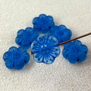 Peut inclure: Six perles en verre bleu en forme de fleur avec un motif en relief. Les perles sont translucides et ont une finition givrée.