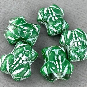 May include: Five green and white star-shaped glass beads with a marbled pattern.