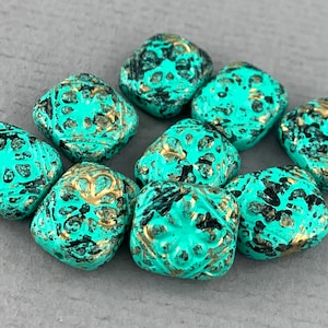 May include: Ten square turquoise glass beads with gold and black accents. The beads have a distressed look and are perfect for jewelry making.