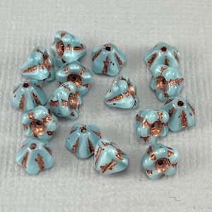 May include: A collection of light blue, flower-shaped beads with copper-colored accents. The beads have a textured surface and a hole for stringing. These beads are suitable for jewelry making and craft projects.