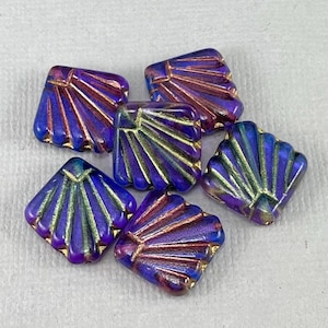 May include: Six square-shaped glass beads with a purple and gold iridescent finish. Each bead features a raised design of a fan or shell.