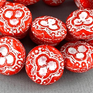 May include: Red and white glass beads with a floral design. The beads are round and have a textured surface.