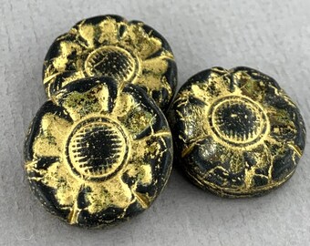 May include: Three black and gold glass buttons with a raised flower design. The buttons have a distressed look with gold paint flaking off.
