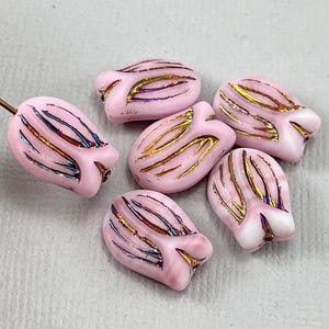May include: Six pink glass beads shaped like tulips with gold and iridescent accents.