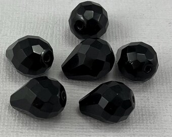 May include: Six black faceted teardrop-shaped glass beads. The beads are approximately 2.5 cm in length.