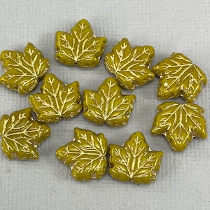 Peut inclure: Dix perles en verre en forme de feuille d'érable de couleur dorée. Les feuilles ont un motif en relief et sont parfaites pour la fabrication de bijoux ou l'artisanat.