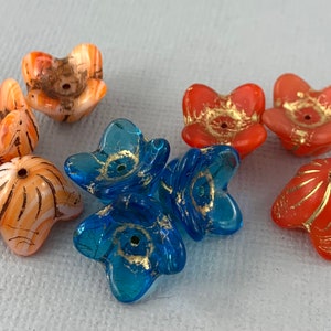 May include: Assortment of colorful glass flower beads with gold accents. The beads are in shades of orange, blue, and white.