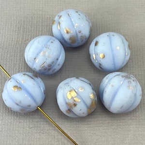 May include: Six light blue glass beads with gold flecks. The beads are round and have a textured surface.