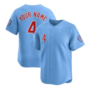 Könnte beinhalten: Hellblaues Baseball-Trikot mit der roten Nummer 4 auf Vorder- und Rückseite. Auf der Rückseite des Trikots steht "YOUR NAME" in roter Schrift über der Nummer. Ein Teamlogo befindet sich auf dem linken Ärmel.