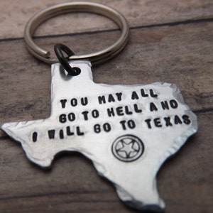 May include: A silver-colored keychain in the shape of Texas. The keychain has the text "YOU MAY ALL GO TO HELL AND I WILL GO TO TEXAS" stamped on it. A silver key ring is attached.