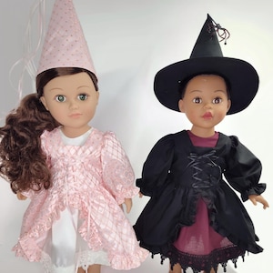 Puede incluir: Dos muñecas vestidas con disfraces. Una muñeca lleva un vestido de princesa rosa y un gorro puntiagudo a juego. La otra muñeca está vestida de bruja, con un vestido negro, un sombrero negro y una camiseta burdeos.