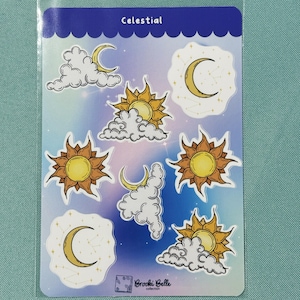 May include: A sheet of celestial themed stickers featuring suns, moons, and clouds. The stickers are on a white background with a blue and purple gradient. The text "Celestial" is at the top of the sheet. The text "Brockie Belle collection" is at the bottom of the sheet.