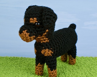 May include: A crocheted Rottweiler dog toy with black and brown fur. The toy has black eyes and a brown nose.
