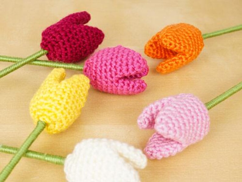 Op de afbeelding: Vijf gehaakte tulpen in verschillende kleuren: roze, geel, wit, oranje en rood. De tulpen zijn handgemaakt en hebben een steel.