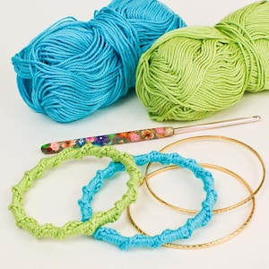 May include: Two balls of yarn, one blue and one green, with two crocheted bracelets and a crochet hook.