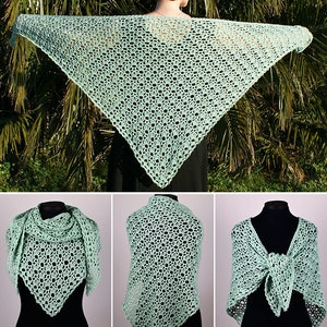 May include: A light green crochet shawl with a delicate openwork pattern. The shawl is shown draped over a mannequin and worn by a person.