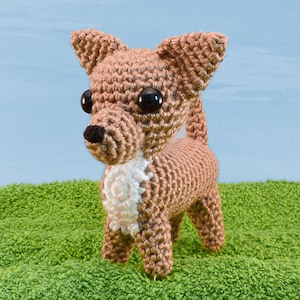 May include: A crocheted brown and white chihuahua dog toy with black eyes.