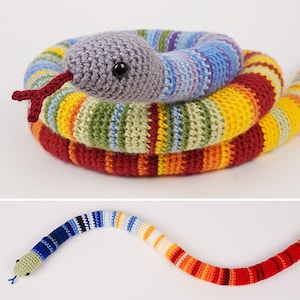 May include: A colourful crocheted snake toy with a grey head and red tongue. The snake is coiled in a circle and has a long, thin body.