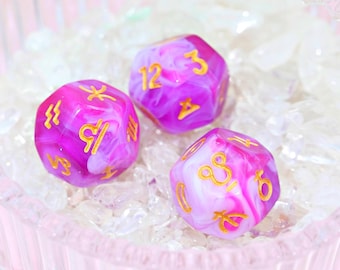 May include: Three pink and white swirl dice with gold zodiac symbols. The dice are on a bed of white crystals.
