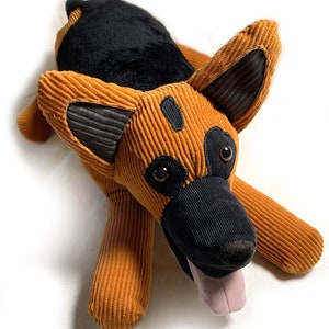 May include: A plush brown and black German Shepherd dog toy with a pink tongue sticking out. The dog has a corduroy texture and black eyes.