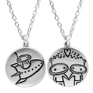 One side depicts two aliens holding hands with a single heart between their heads. The reverse side depicts an astronaut in a cartoon space ship.
