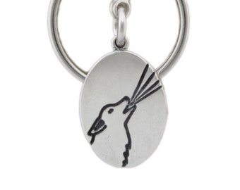 May include: Silver-toned keychain with a round clasp and a split ring. An oval pendant features a black howling wolf design. The keychain is made of metal and is suitable for keys or as a decorative accessory.