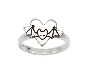 May include: A silver ring with a heart-shaped design featuring a bat inside. The ring is marked "STERLING" on the inside band.