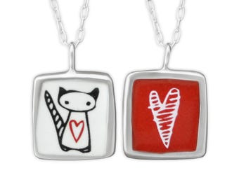 May include: Two silver necklaces with square pendants. One pendant features a black and white illustration of a cat with a red heart on its chest. The other pendant features a red background with a white heart.