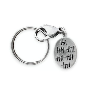 May include: Silver keychain with a round charm featuring tally marks. The charm has a silver ring attached to a silver split ring.