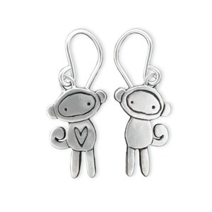 May include: A pair of silver monkey earrings with a heart on one monkey. The earrings are made of metal and have a simple design.