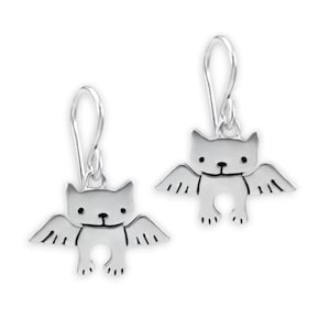 May include: Silver dangle earrings featuring a cute cartoon cat with wings. The cat has a simple, smiling face and small, rounded wings.
