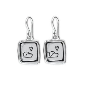 May include: A pair of silver-toned dog-themed earrings. Each earring features a square pendant with a black outline, a heart, and a minimalist dog illustration. The earrings have a hook closure.