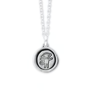 May include: A silver-colored pendant necklace featuring a circular charm with a raised monkey design. The monkey is depicted with outstretched arms and a curled tail. The necklace chain is also silver.