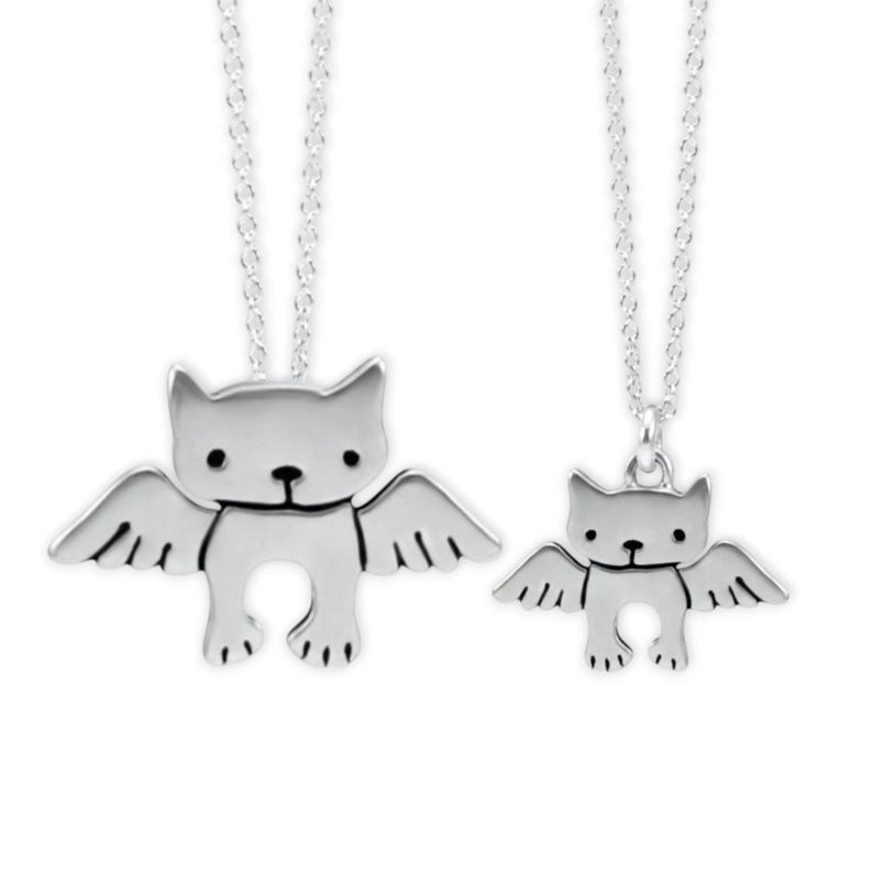 Puede incluir: Dos collares de plata con un colgante de gato con alas. El colgante m&aacute;s grande est&aacute; en una cadena m&aacute;s larga y el colgante m&aacute;s peque&ntilde;o est&aacute; en una cadena m&aacute;s corta.