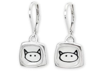 May include: Silver dangle earrings with a square-shaped charm featuring a black and white cartoon cat face.