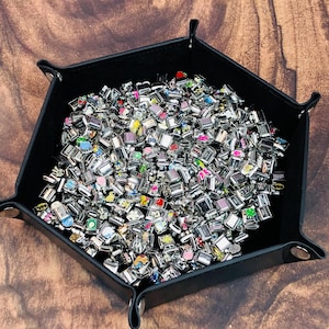 May include: A black leather tray filled with a large collection of colorful charm beads. The beads are silver with various designs and colors.