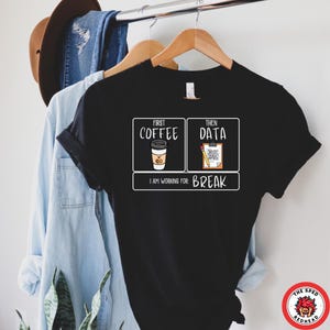 Könnte beinhalten: Schwarzes T-Shirt mit einer weißen Grafik, auf der "First Coffee Then Data I am working for: Break" steht. Die Grafik zeigt eine Tasse Kaffee und eine Klemmbrett mit einem Bleistift.