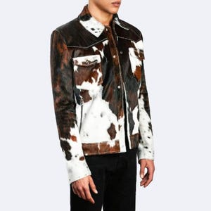 May include: A brown and white cowhide jacket with a button-up front and a zipped pocket on the left side.