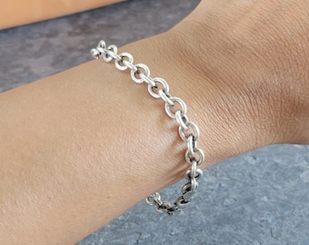 May include: A silver chain bracelet with a simple, classic design. The bracelet is made of a series of interlocking circles.