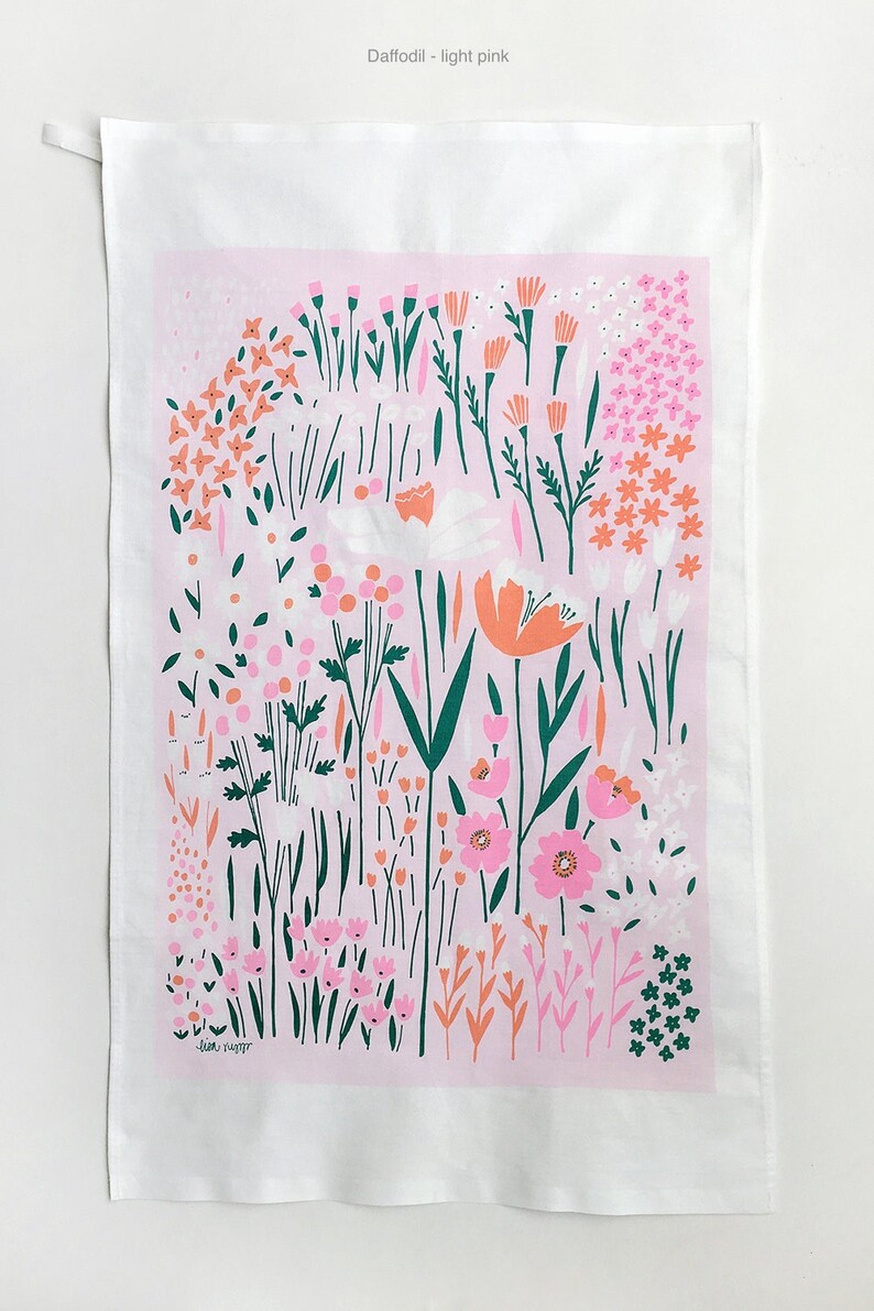 May include: A pink tea towel with a floral pattern featuring pink, orange, and green flowers. The text "Jean-Harper" is printed in the bottom left corner.
