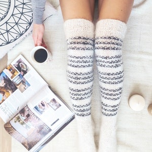 May include: A pair of white and gray striped knitted thigh-high socks. The socks are made of a soft, fluffy yarn and have a cozy, comfortable look.