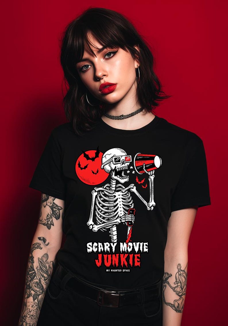 Pode incluir: Camiseta preta com um desenho de esqueleto usando &oacute;culos 3D e segurando um megafone vermelho. Uma lua vermelha e morcegos no fundo. O texto na camiseta diz "SCARY MOVIE JUNKIE" e "MY HAUNTED SPACE".