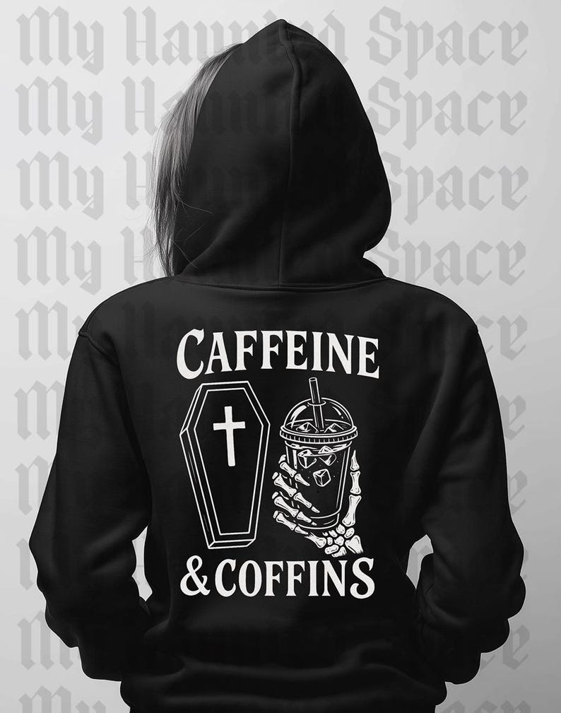 May include: Black hoodie with the text "CAFFEINE & COFFINS" in white. The design includes a coffin with a cross and a skeleton hand holding a drink with ice cubes. The hoodie has a hood.