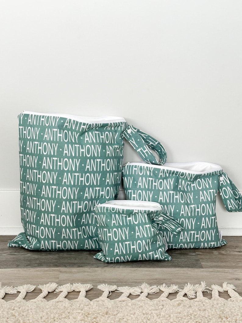 May include: Set of three teal zippered pouches with white text that reads 