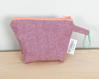 May include: A small, pink zippered pouch with a peach-coloured zip and a mint green carabiner. The pouch has a textured fabric and a small tag that reads "PETUNIAS by Kelly."