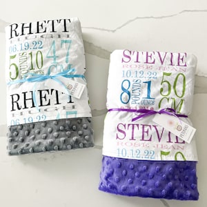 Puede incluir: Dos mantas de beb&eacute; personalizadas con tejido minky gris y morado. Las mantas presentan un tejido blanco con texto colorido, incluyendo nombres, fechas de nacimiento, pesos y longitudes. El texto en la manta gris dice: "Rhett Hugh 06.19.22 5 libras 10 onzas 47 cm". El texto en la manta morada dice: "Stevie Rose Jean 10.12.22 8 libras 1 onza 50 cm".